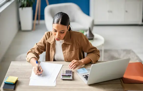 a woman sitting at a desk writing on a piece of paper