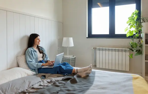 a woman sitting on a bed with a laptop
