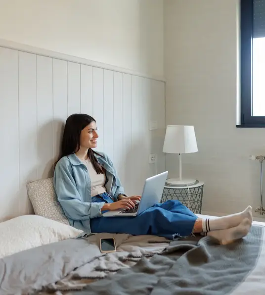 a woman sitting on a bed with a laptop
