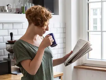 a woman holding a coffee cup and newspaper