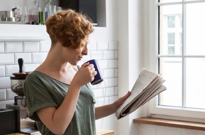 a woman holding a coffee cup and newspaper