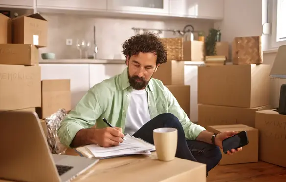 a man sitting in a room with boxes and a laptop